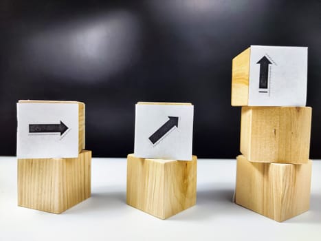 Wooden cubes with arrows and percentages on black background. Stages of action and goal achievement. Planning. Business actions. Receiving income and profit