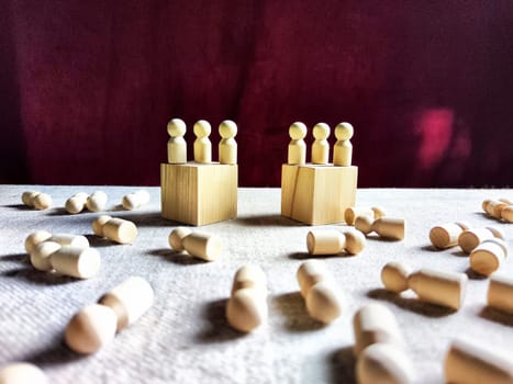 Wooden toys stand opposite and lot of lying figures. Concept of dispute between leaders of two groups. Government and deaths of citizens and soldiers. War in Russia, Ukraine, Israel, Palestine