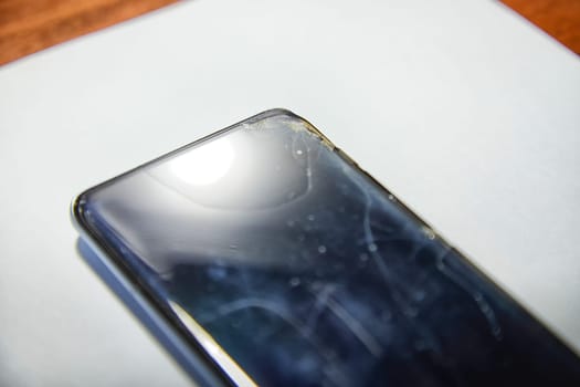 Close-Up View of a Cracked Smartphone Screen Against White Background. the detailed texture of a shattered smartphone screen, emphasizing extensive damage to the device