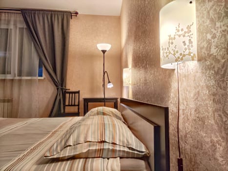 Small compact stylish bedroom in stylish soothing colors with double bed. Concept of small cozy bedroom, hotel room