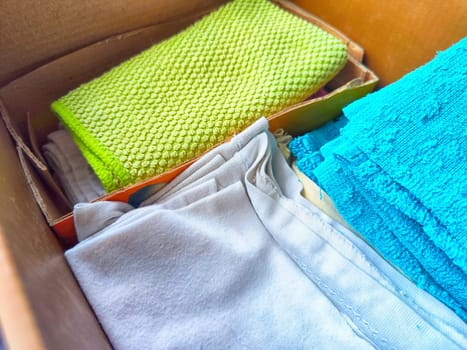 Old rags and eco-friendly cleaning cloths neatly arranged in a cardboard box. Old rags and things for cleaning and cleanliness in the house. Eco-friendly use of recyclables