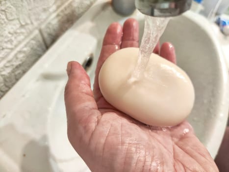 Close-up of a persons hands with soap being rinsed under stream of clear water, symbolizing hygiene and cleanliness