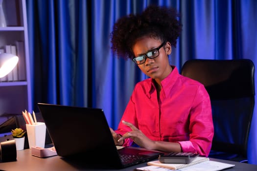 African woman businesswoman or blogger wearing pink shirt with serious face, looking and focusing on screen laptop with struggle project. Concept of stressful expression at work from home. Tastemaker.