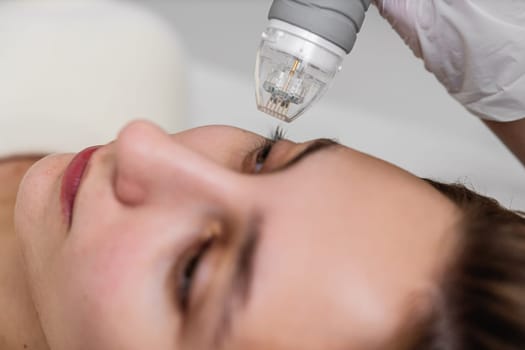 A woman is undergoing a laser treatment on her eye, with the help of a specialist ensuring safety and precision.