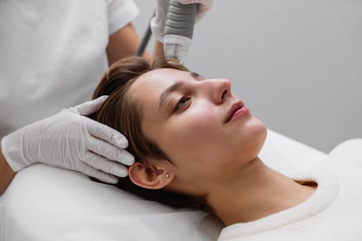 A woman is undergoing a laser treatment on her face, focusing on various areas including the nose, cheeks, smile lines, mouth, and eyelashes.