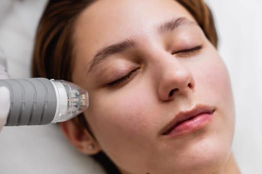 The woman is receiving a facial treatment with a machine on her nose, cheeks, skin, lips, eyelashes, and eyes.