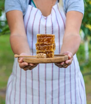 A woman holds honey in the garden. Selective focus. Nature.