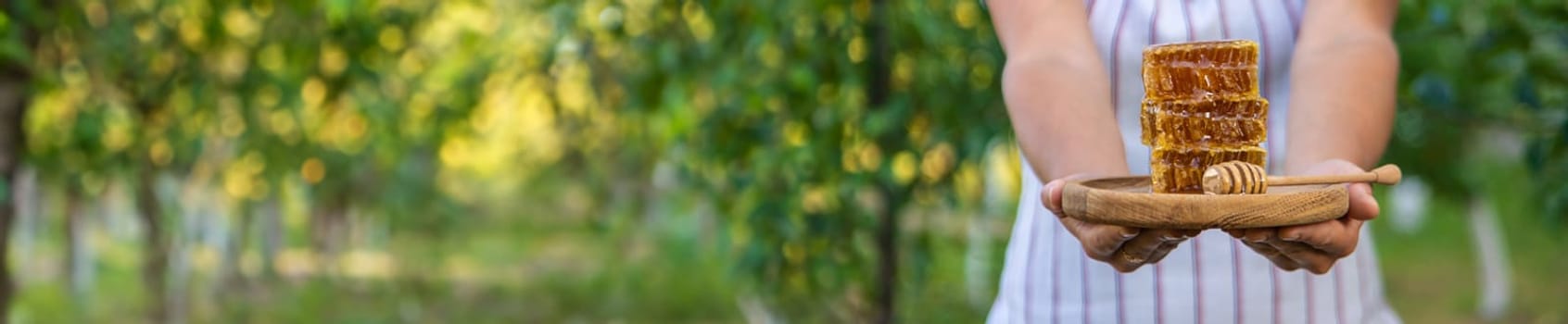 A woman holds honey in the garden. Selective focus. Nature.