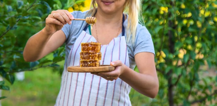 A woman holds honey in the garden. Selective focus. Nature.