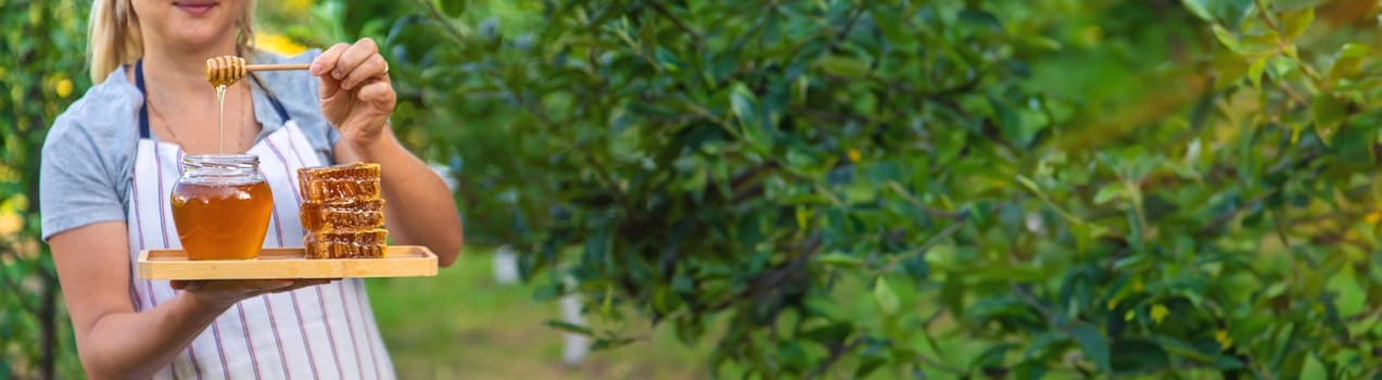 A woman holds honey in the garden. Selective focus. Nature.