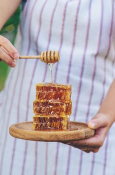 A woman holds honey in the garden. Selective focus. Nature.