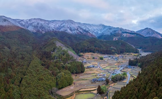 Aerial view of terraced rice fields in small village by snowy mountains. High quality photo