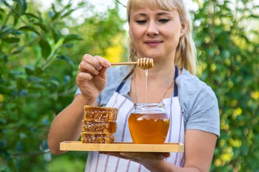 A woman holds honey in the garden. Selective focus. Nature.