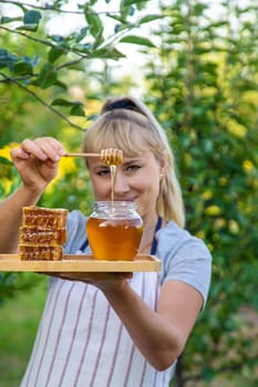 A woman holds honey in the garden. Selective focus. Nature.