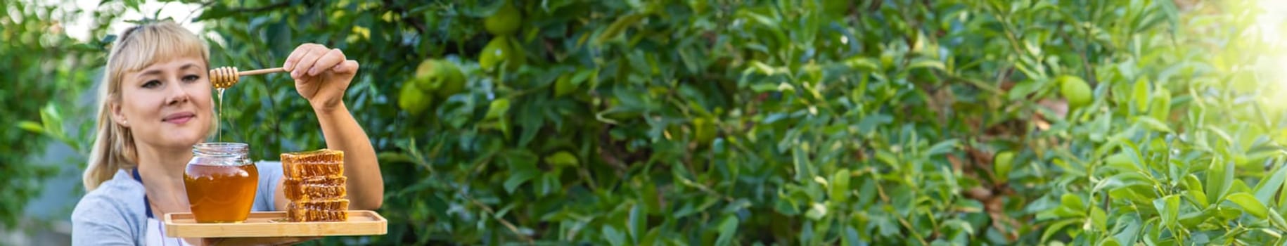 A woman holds honey in the garden. Selective focus. Nature.