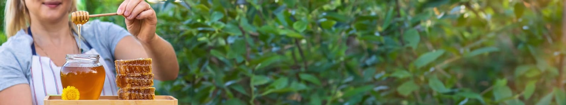 A woman holds honey in the garden. Selective focus. Nature.