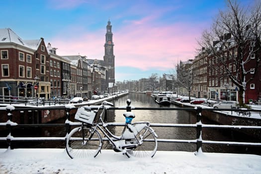 Amsterdam covered with snow with the Westerkerk in winter in the Netherlands