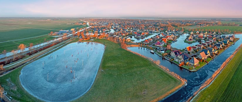 Aerial view on the traditional village Koudum with the ice rink in Friesland the Netherlands at sunset in winter