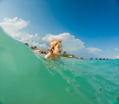 Joyful boy plays in the sea, creating playful splashes and enjoying the waves.