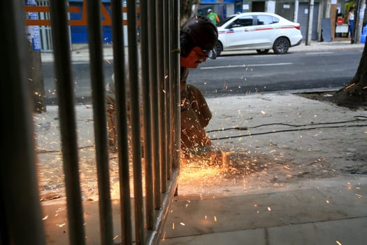 salvador, bahia, brazil - january 25, 2024: worker uses cutting disc to cut metal at a construction site in the city of Salvador.