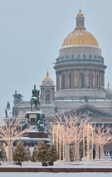 Russia, St Petersburg, 30 December 2023: people walk among Christmas trees in heavy snowfall, a park organized on holidays near St. Isaac's Cathedral and the monument to Emperor Nicholas II. High quality photo