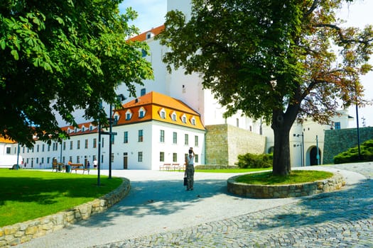 White castle building in Bratislava on a sunny day and a tourist in the distance, Slovakia