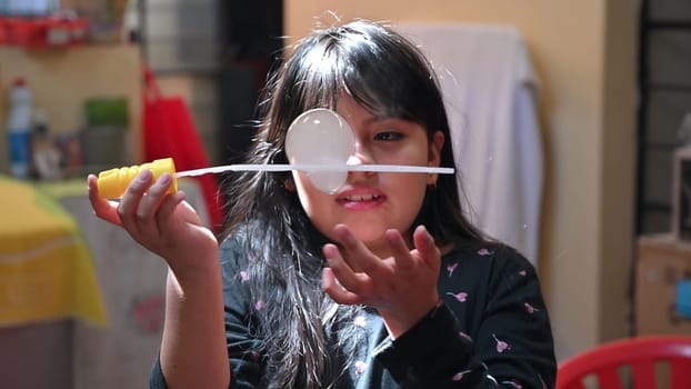 A cute little girl blowing soap bubbles inside her house