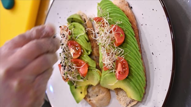 Avocado toast with small tomatoes on rye bread toast with soft cheese and sprouts. Healthy breakfast