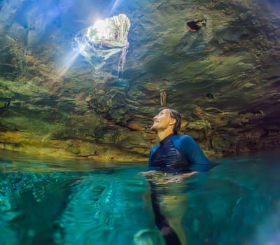 Man immersed in the enchanting beauty of a Mexican cenote, surrounded by crystal-clear waters and captivating natural formations.