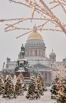 Russia, St Petersburg, St. Isaac's Cathedral and the monument to Emperor Nicholas II through lighting decorations during snowstorm, streets decorated for Christmas. High quality photo