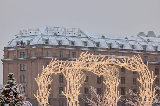 Russia, St Petersburg, 30 December 2023: Hotel Astoria through Christmas trees in heavy snowfall, a park organized on holidays near St. Isaac's Cathedral. High quality photo