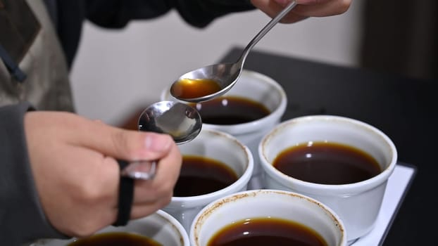 Professional barista tasting different types of coffee in cup tasters. Coffee degustation