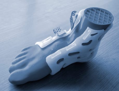 Medicine splint corset prosthesis langet for foot and model human foot printed on 3D printer from molten plastic. Medical orthosis, fixator, plastic overlay for leg and human leg created on 3D printer