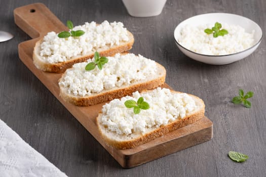 Bread with curd cheese on wooden board.