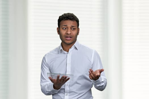 Indian business coach using futuristic digital tablet. Young dark-skinned business man giving a presentation on white background.