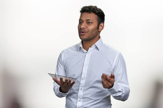 Young indian executive speaker holding blank futuristic digital tablet. Business coach with glass tablet on blurred background.