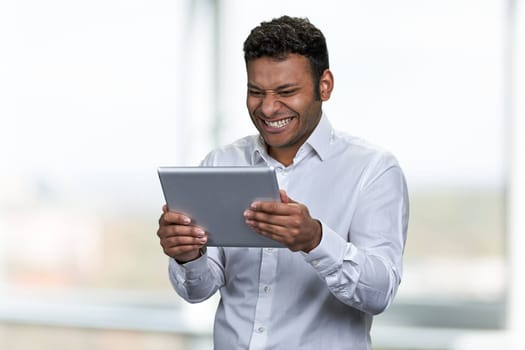 Happy cheerful businessman looking at digital tablet pc. People, technology and lifestyle concept.