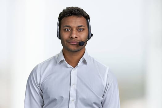 Handsome consultant of call center in headset looking at camera. Portrait of call center agent on blurred background.