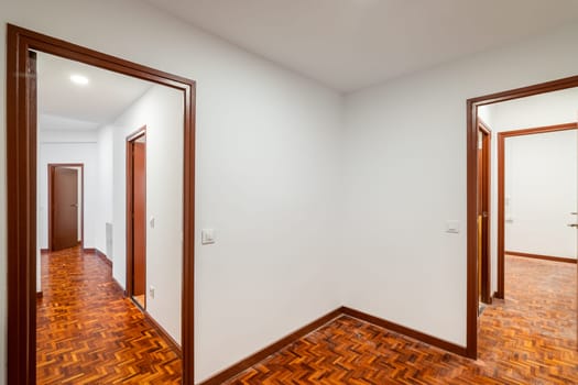 An apartment with corridor leading to empty rooms with wooden doors.