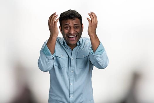 Happy laughing young man looking at camera standing on blurred background. Positive human expressions.