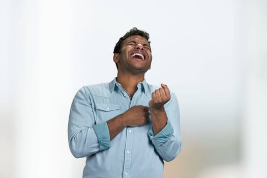 Young indian man is laughing out loud standing on blurred background. It was funny joke.