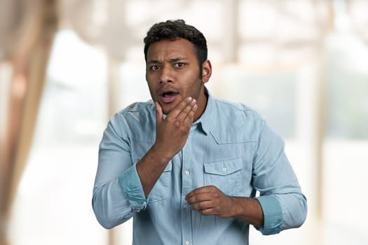 Young handsome indian man is preening before date. Blur interior background.