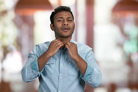 Attractive young indian guy is preening before date. Interior blur background.