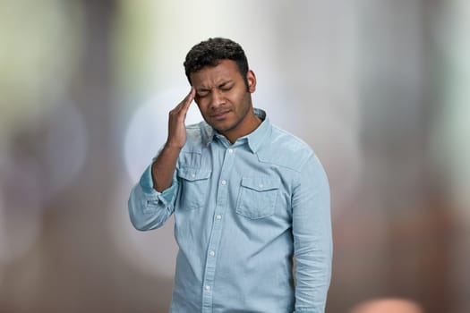 Young asian man suffering from headache. Abstract bokeh background. Health problem concept.