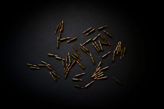 Cartridges from a Kalashnikov assault rifle close-up, lie on a dark gray background, a concept on the theme of war, resistance and crisis.