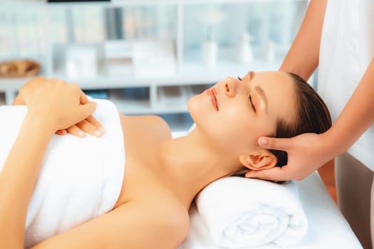 Caucasian woman enjoying relaxing anti-stress head massage and pampering facial beauty skin recreation leisure in dayspa modern light ambient at luxury resort or hotel spa salon. Quiescent