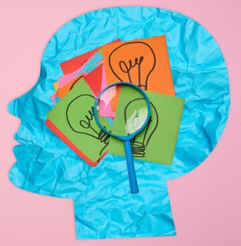 Silhouette of a human head and stickers with drawn electric lamps on a pink background, search for new ideas and solutions