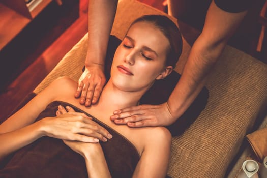 Caucasian woman customer enjoying relaxing anti-stress spa massage and pampering with beauty skin recreation leisure in warm candle lighting ambient salon spa at luxury resort or hotel. Quiescent