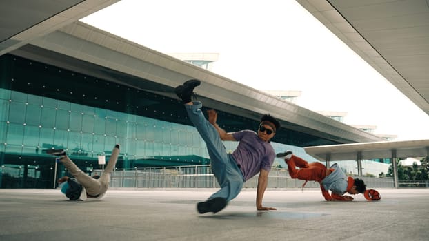 Group of diverse hipster or street dancer doing head spin in front of mall. Happy energetic break dancer practice b-boy step dancing with friends. Outdoor sport 2024. Street dancer concept. Sprightly.