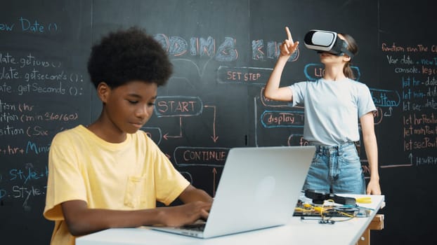 Smart african student programing and coding innovative system while caucasian girl enter in metaverse or virtual world by using VR or head set at blackboard in STEM technology classroom. Edification.